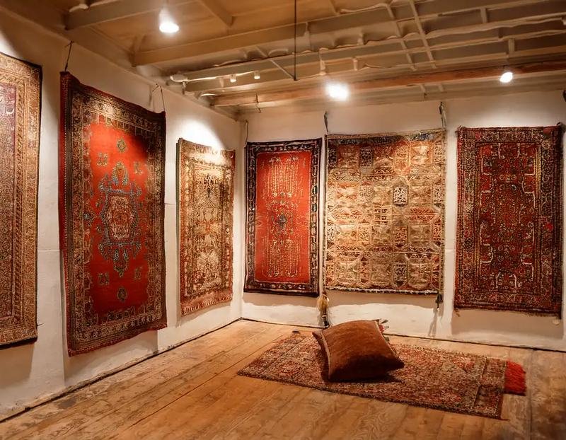 Tapis d’Orient présentés déroulés et empilés dans une galerie de dépôt-vente