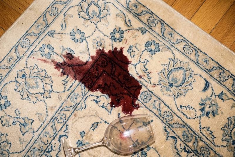 Tache de vin rouge en cours d’extraction sur le champ ivoire d’un tapis d’Orient