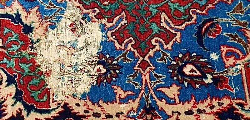 Lacune de velours sur fond bleu d’un tapis persan, trame de coton à nu