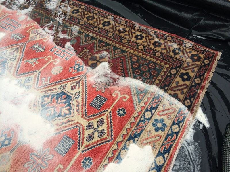 Tapis persan rouge recouvert de mousse de lavage pendant le nettoyage à la main