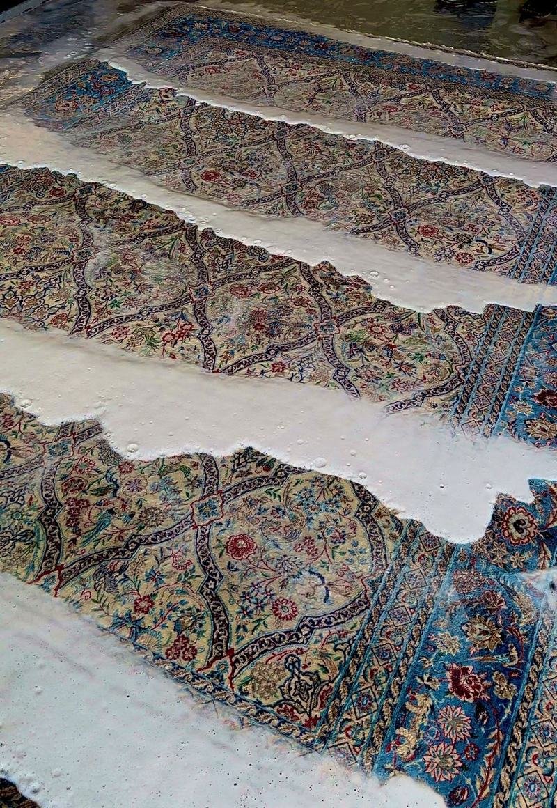 Tapis persans posés à plat au sol de l’atelier pendant le rinçage