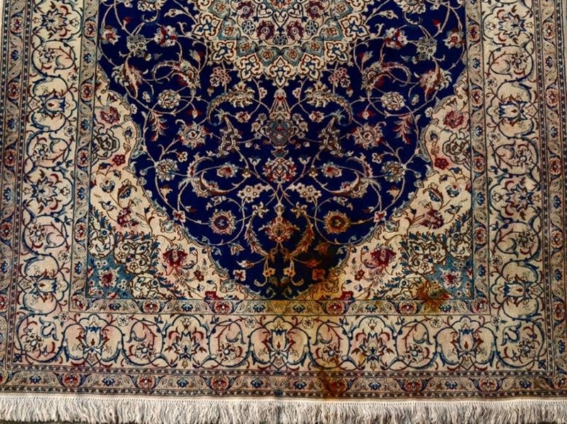 Grande tache brune sur le champ bleu et ivoire d’un tapis Naïn