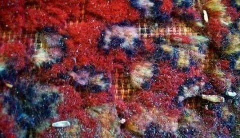 Macro de l’usure du velours d’un tapis rouge, fibres coupées